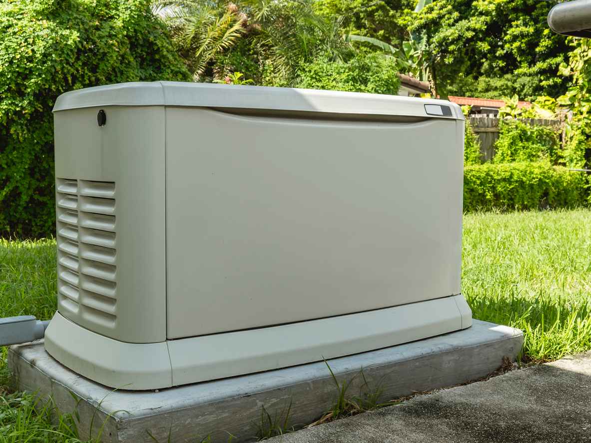 A Home Standby Generator installed at the backyard of a house. An air-cooled natural gas or liquid propane generator for residential use.
