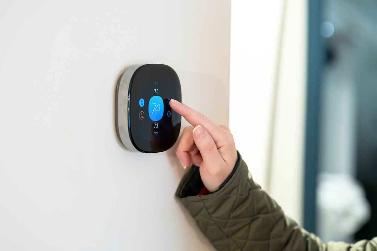 woman adjusting temperature on digital thermostat